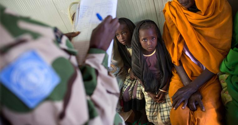 A peacekeeper from Nigeria registers a woman and two children so they can see a health professional