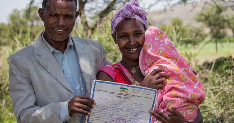 Two parents proudly show off their baby's birth certificate